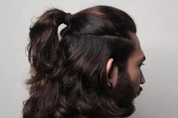 man staring at the wall with a ponytail in his hair