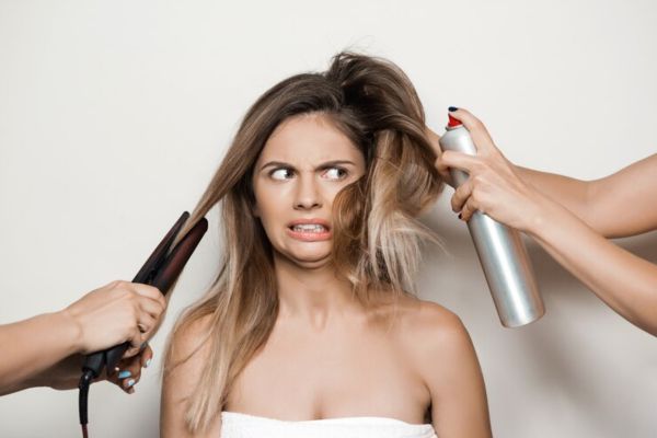 a woman with a hair dryer and hair straightener with dehydrated hair