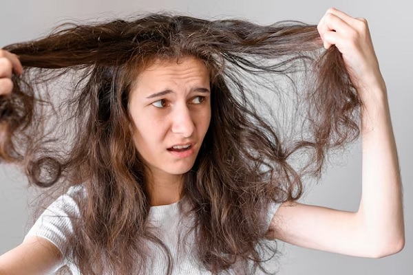 a woman looking at her hair after not protecting hair from sun damage
