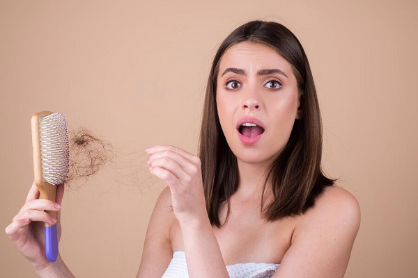 Young woman with a brush in her hand showing hair loss