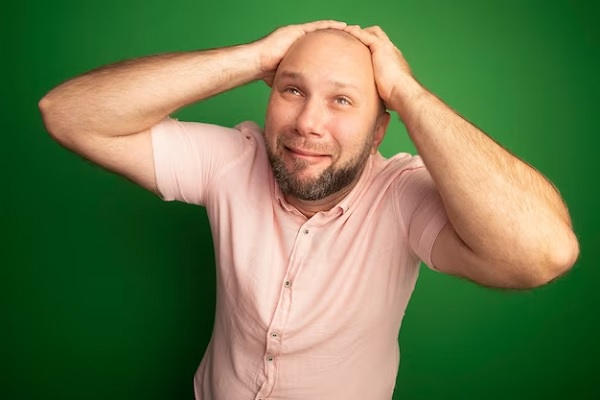 a man holding his bald head while looking upwards