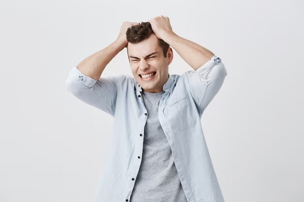 Visibly affected man with his hands on his head on a light blue background