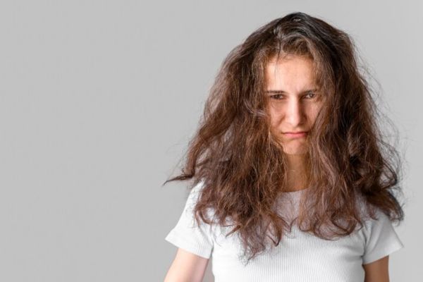 woman with frizzy hair looking angry and sad at the camera