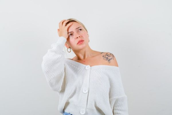 a worried woman with her hand on her head thinking about her female alopecia