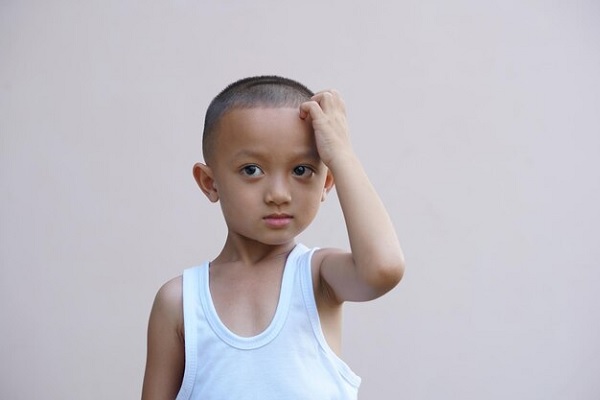 a kid touching his head wondering about hair transplant children