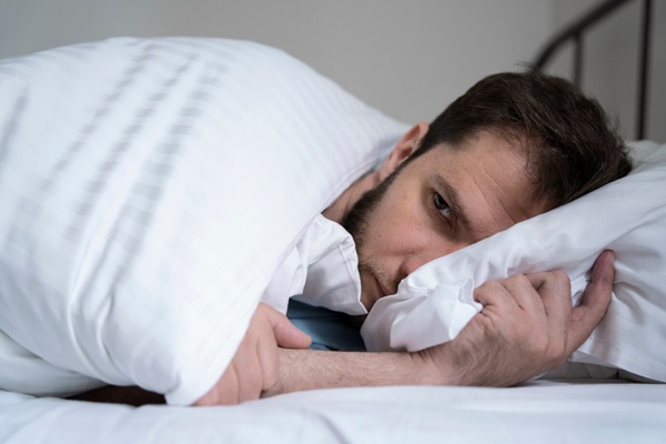 Anxious man lying in bed medium shot