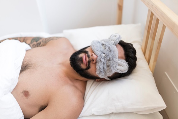 Man sleeping in bed wearing sleep mask